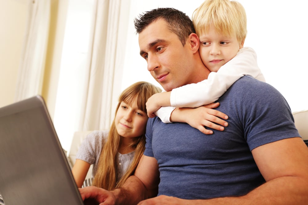 Father with children working on laptop computer at home