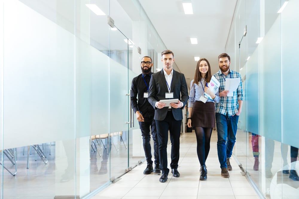 Full length of group of happy young business people walking the corridor in office together-1