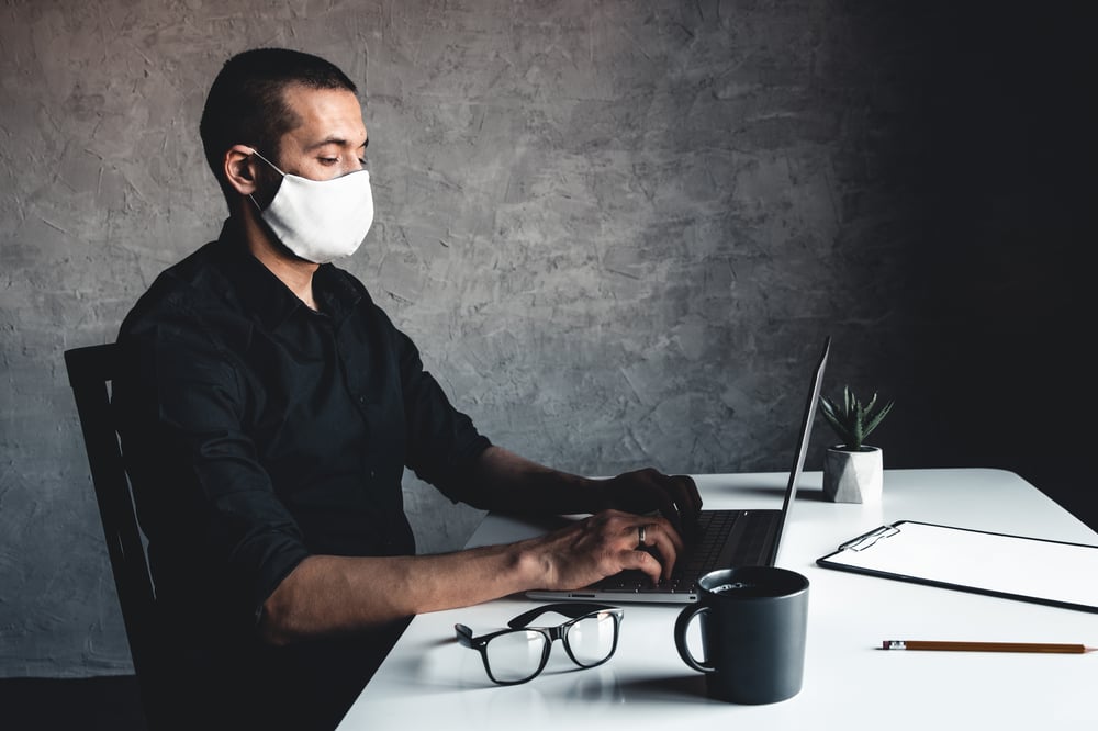a-masked-man-works-at-a-computer-pandemic-coronavi-P7AH6B2