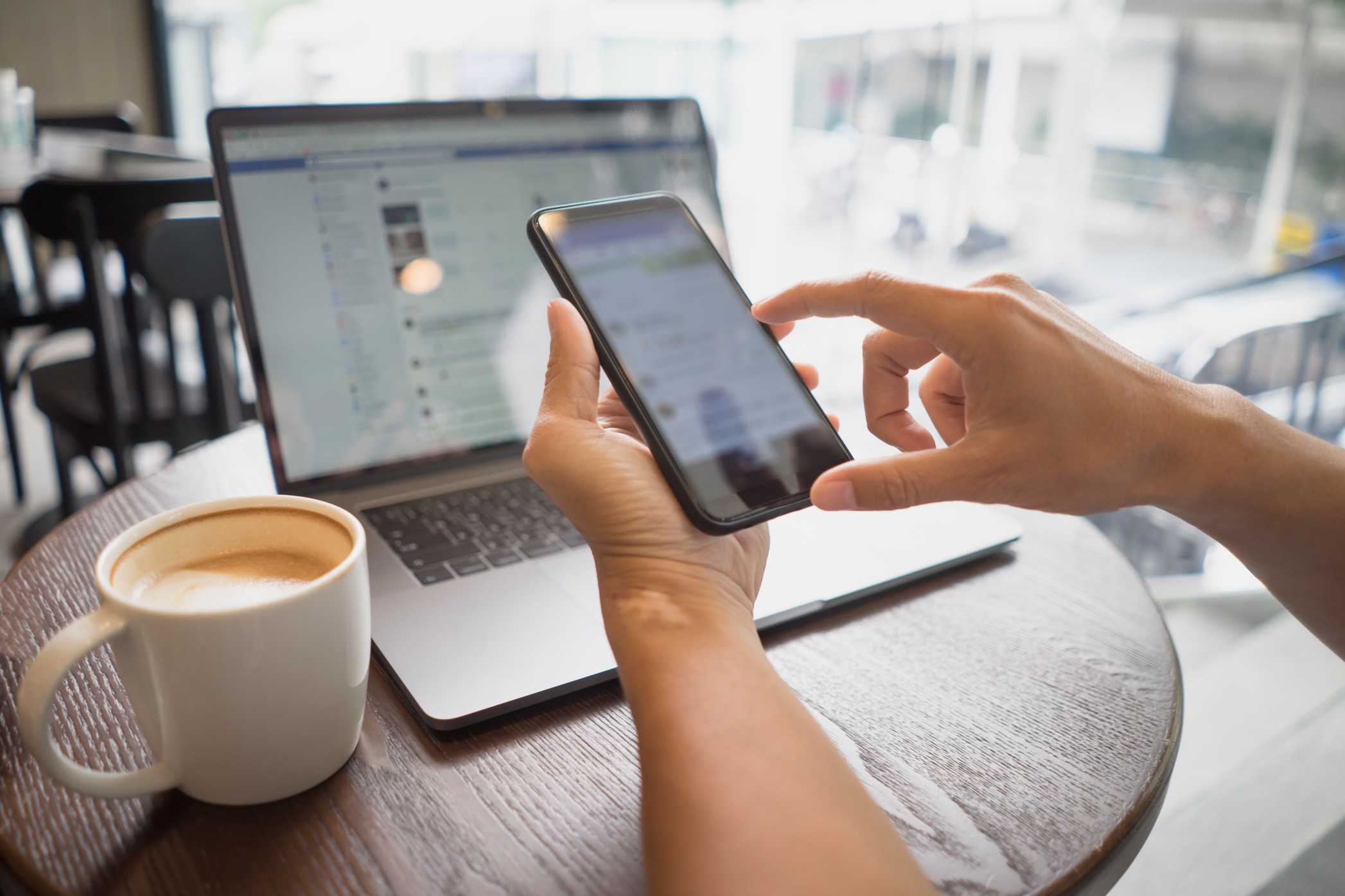 business-man-hand-holding-smart-phone-touch-or-typing-on-social-media-app-with-coffee-cup-and-laptop_t20_nRAGQg