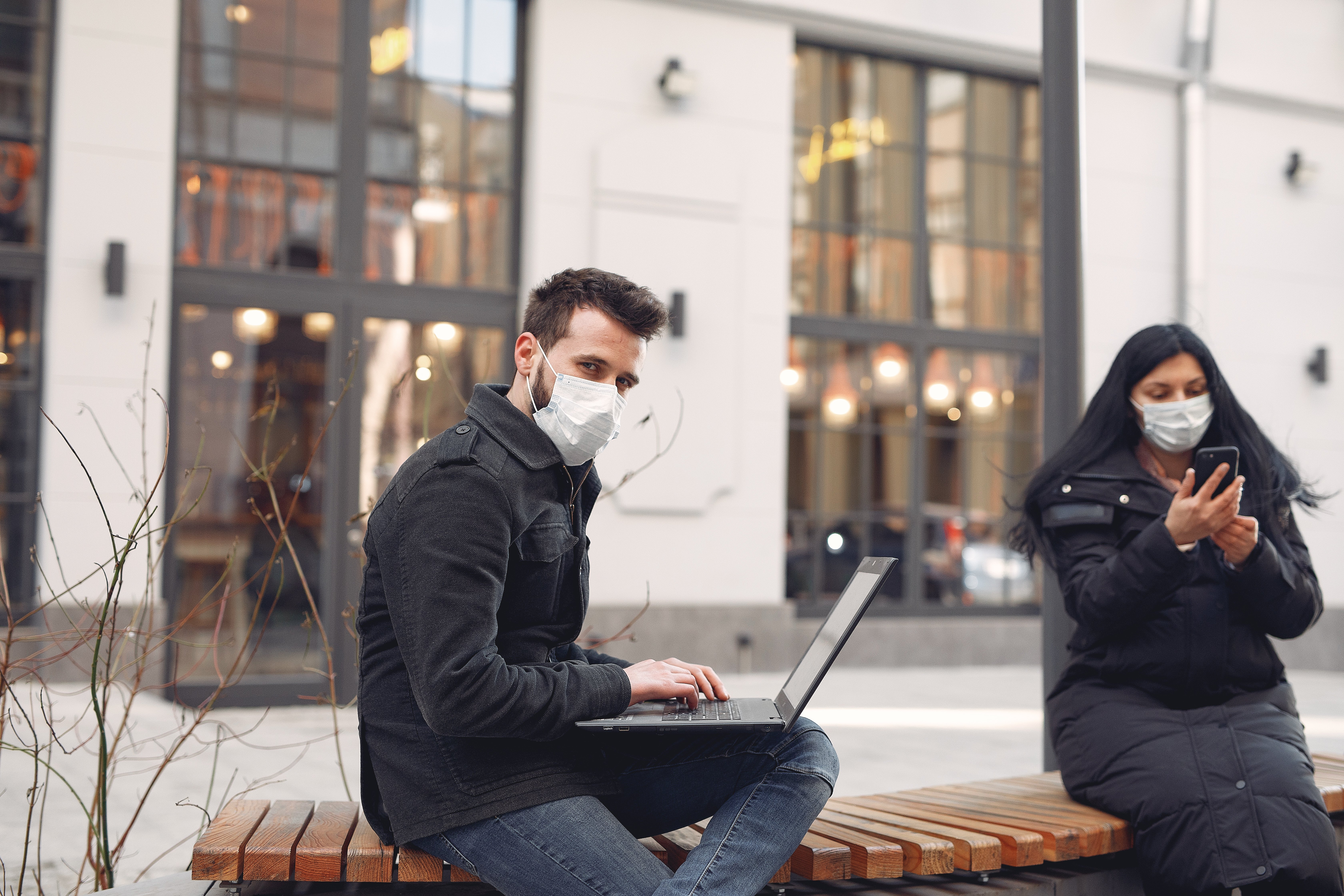 people-in-a-masks-sitting-in-a-city-with-a-laptop-ZSPK9D9