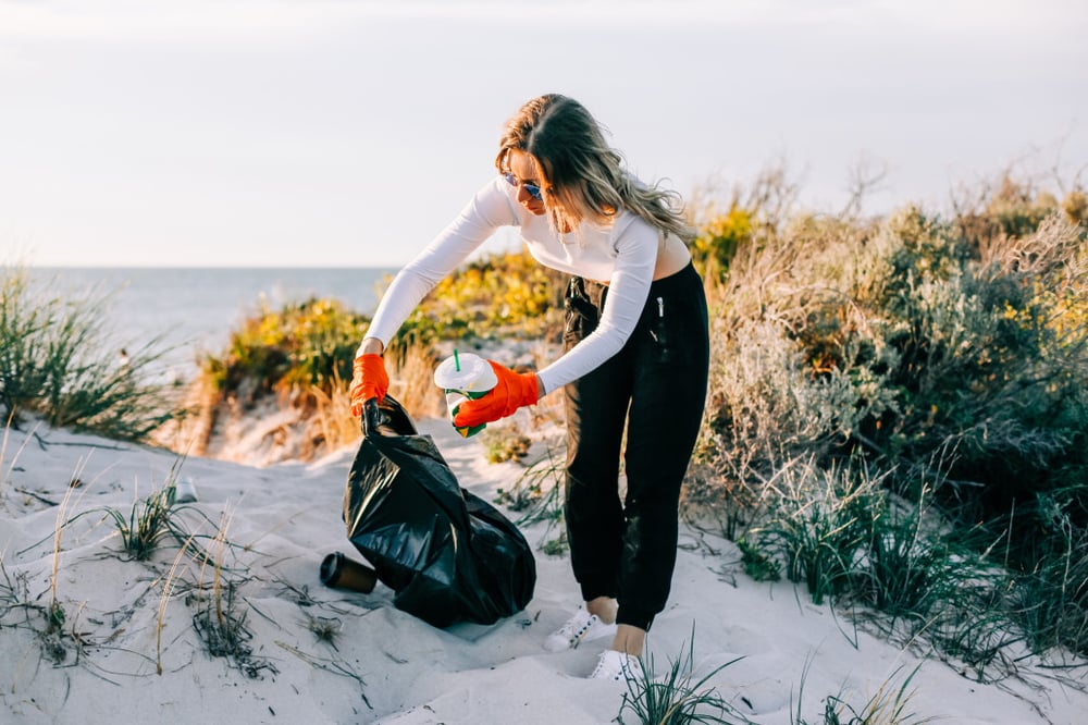 picking-up-trash-picking-up-plastic-waste-in-a-bin-bag-at-the-beach-volunteer-cleaning-beach-beach_t20_drmb1A