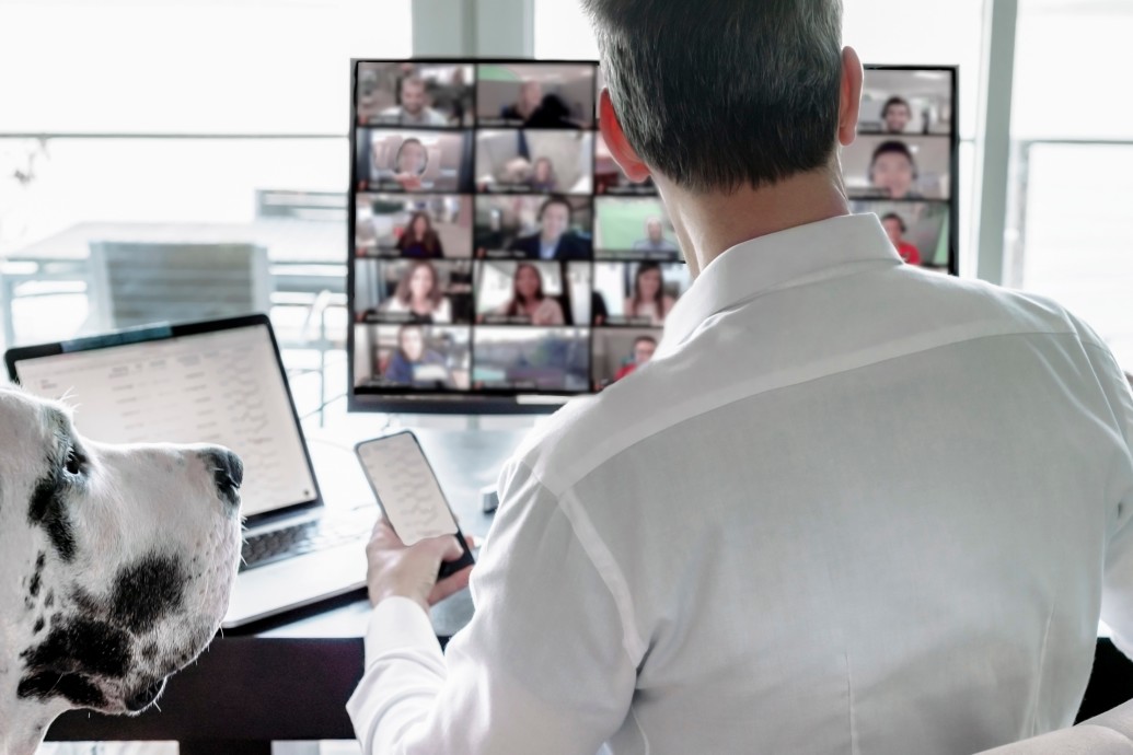 rear-view-of-man-and-pet-dog-sitting-at-table-viewing-a-group-video-chat-screen-rltheis_t20_kL7Lk2