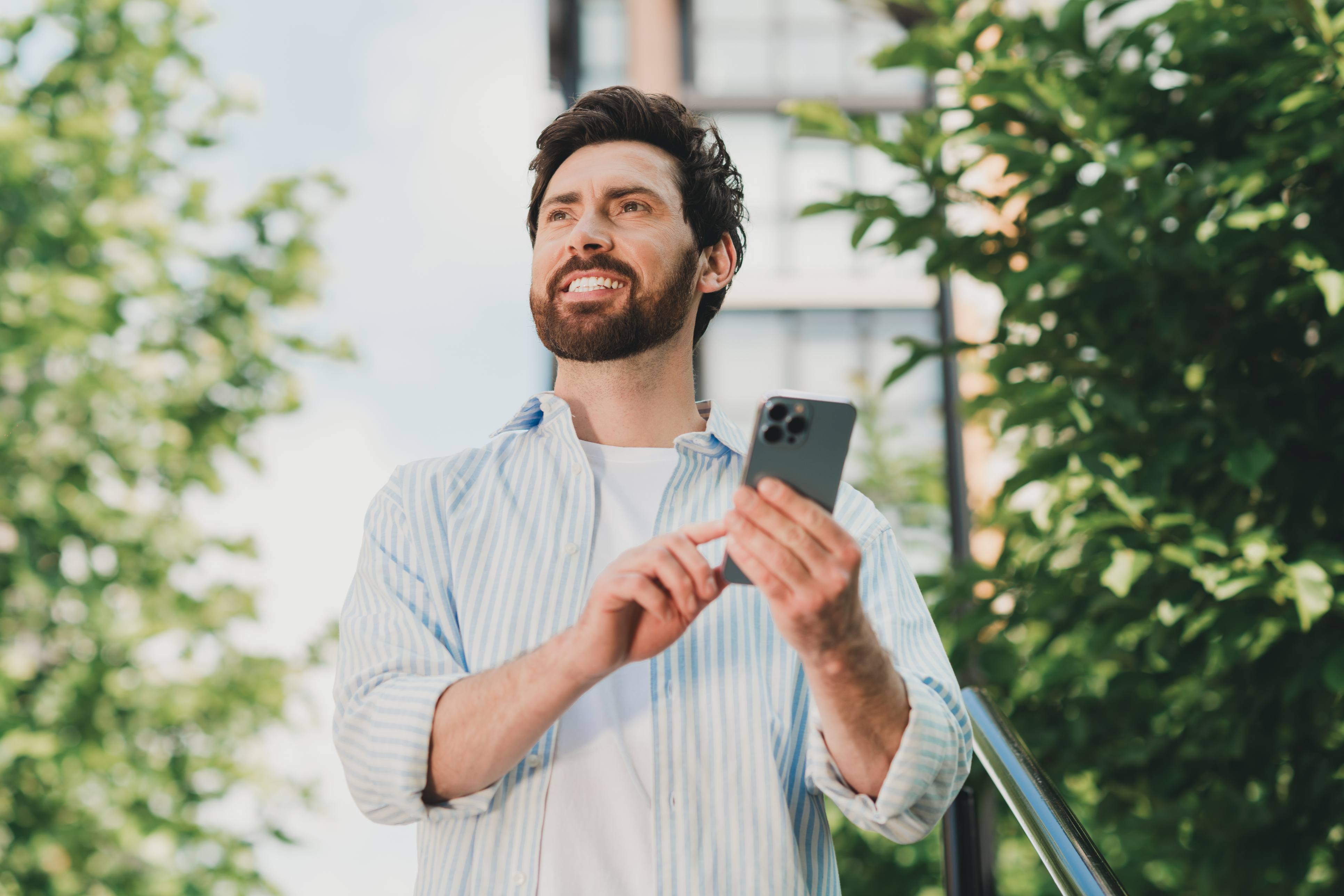 Smiling field sales rep using a white-label sales enablement app on his phone outdoors